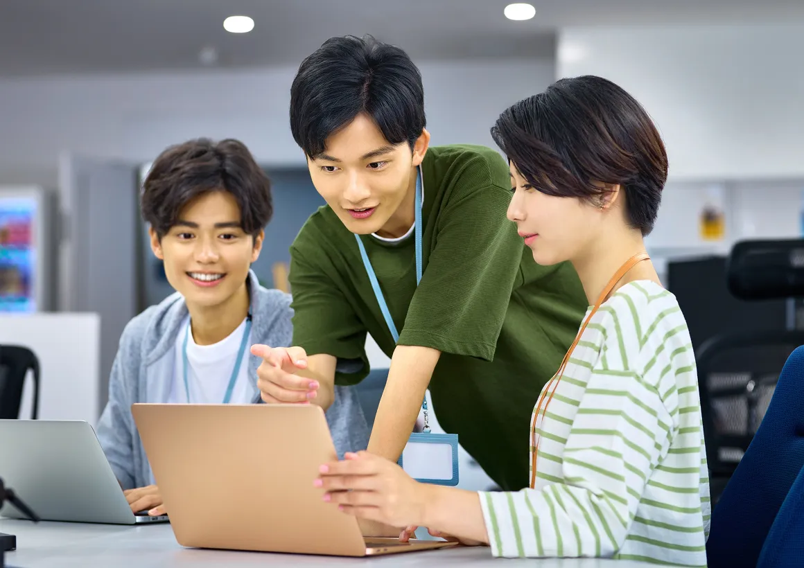 ノートパソコンを見ながら意見を交わす、若手スタッフ同士のチーム作業風景