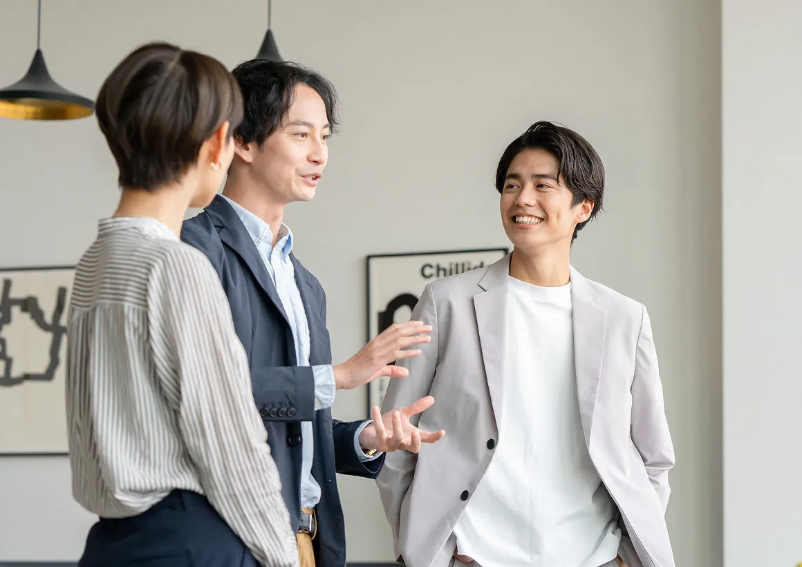 オフィス内で立ち話をしながら、リラックスした雰囲気で意見交換をする社員