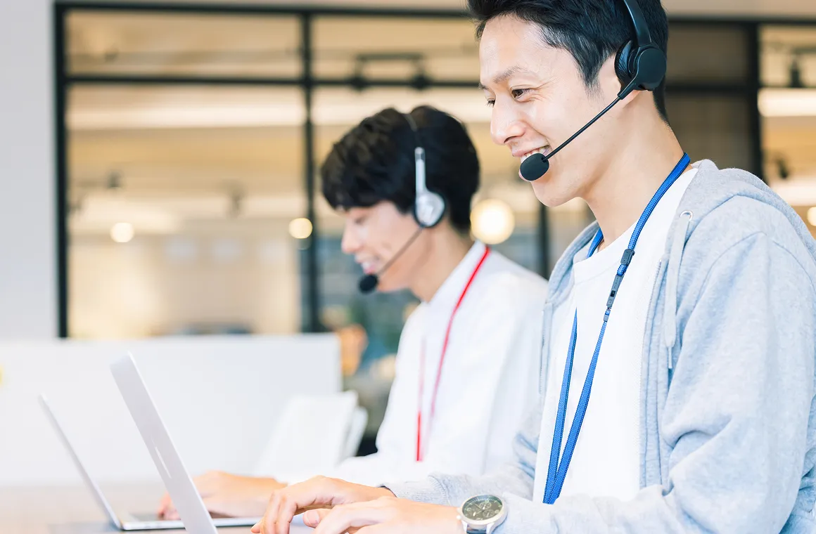 ヘッドセットを着用し、パソコンを操作しながら対応するオフィススタッフ