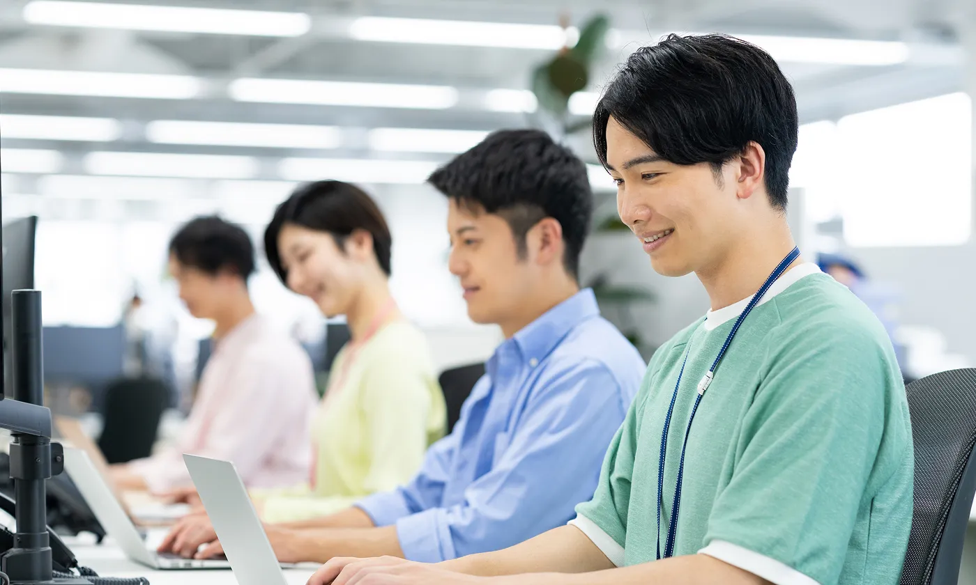 ノートパソコンで業務を行うオフィス内のチームメンバー