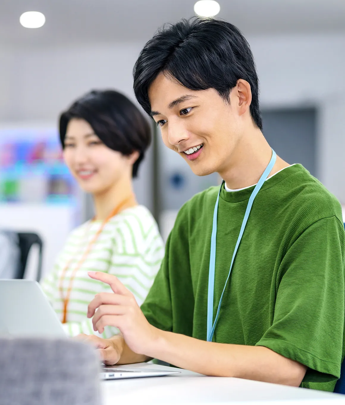 ノートパソコンを操作しながら説明するスタッフと、後ろで見守る同僚